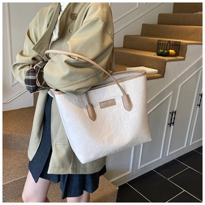 Detail of white tote bag featuring embossed cartoon patterns and brown shoulder straps