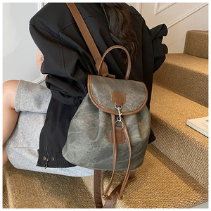 Detail of vintage canvas backpack with brown faux leather trim and metallic hook closure