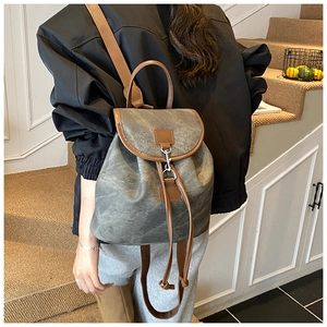 Détail d'un sac à dos rétro en toile grise avec lanières en cuir marron et cordon