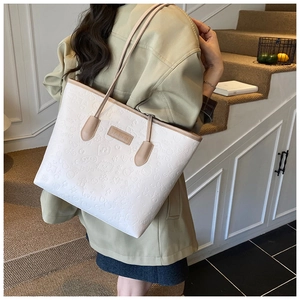 Close-up of white embossed tote bag with heart patterns worn by a model in soft light