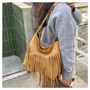 Sac hobo en daim marron avec longues franges et œillets porté par un mannequin