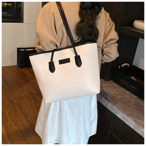 Detail of white embossed tote bag with heart patterns and black contrast straps