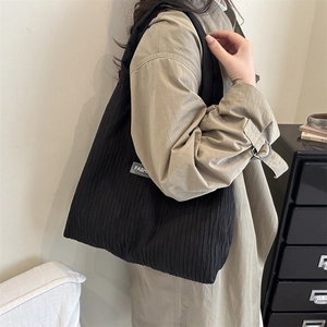 Minimalistische schwarze Plissee-Einkaufstasche mit Fashion-Label an der Schulter
