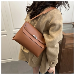 Détail d'un sac porté épaule en cuir marron avec boucle en argent sur un manteau de laine
