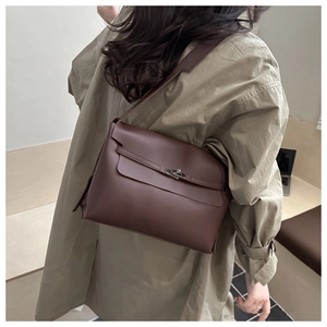 Détail du sac messager en cuir marron foncé avec fermoir rotatif et bandoulière réglable