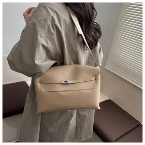 Detail of minimalist beige leather crossbody bag with metal clasp and wide strap on model