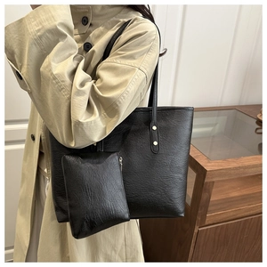 Detail of black faux leather tote bag with grainy texture and golden rivet accents