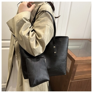 Detail of black leather tote bag featuring a matching zipper pouch and gold rivet accents