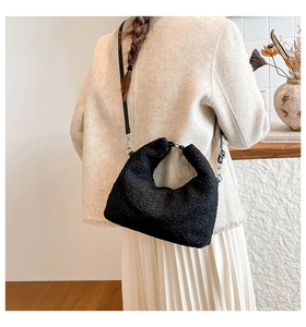Detail of black faux shearling crossbody bag with silver ring handle on a model