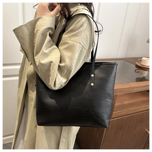 Detail of minimalist black tote bag featuring fine leather texture and gold rivet hardware