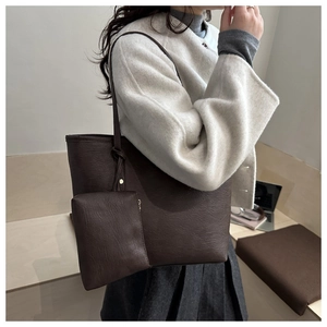 Detail view of stylish dark brown leather tote bag and pouch set on a fashion model