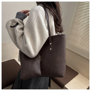 Detail of dark brown tote bag set showing retro leather texture and gold metal rivets