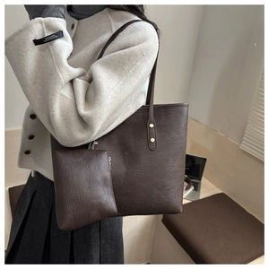 Detail of dark brown faux leather tote bag and matching pouch with gold rivet accents