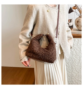 Detail van een bruine teddy hobo tas met lederen schouderband gedragen door model