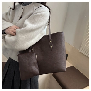 Detail of dark brown faux leather tote bag with gold hardware and matching small pouch