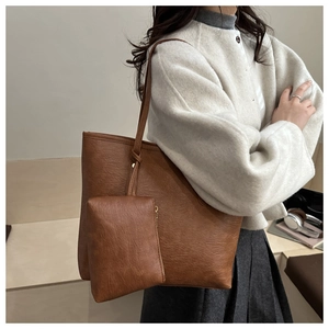 Detail view of large brown tote bag with side pouch shown on model in minimal interior