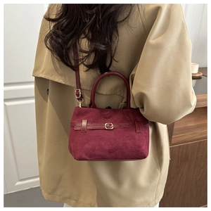 Détail du sac vintage bordeaux avec boucle dorée sur un trench d'automne