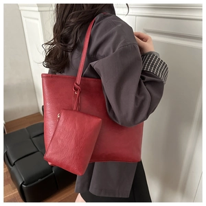 Close-up of red lychee textured leather tote bag with matching zippered pouch detail