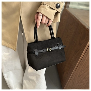 Detail of vintage black suede tote featuring leather strap with gold hardware accents