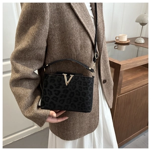 Détail du sac bandoulière noir imprimé léopard avec boucle métallique dorée en forme de V