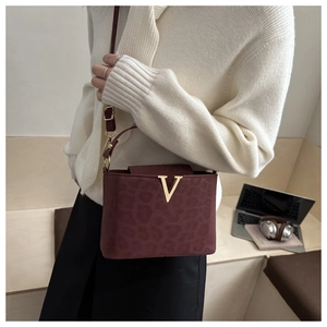 Détail du logo V doré sur le sac à bandoulière bordeaux avec imprimé léopard chic