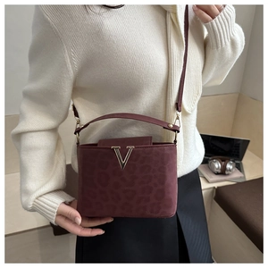 Détail du sac à main bordeaux à motif léopard avec boucle en V dorée et fine bandoulière