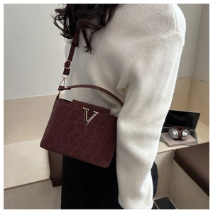 Détail du sac bandoulière bordeaux à motif léopard et logo métallique en V doré