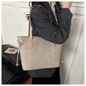 Detail of minimalist beige tote bag showing side drawstring and metal ring decoration