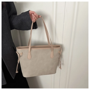 Detail of apricot tote bag featuring leather handles and side drawstring hardware detail