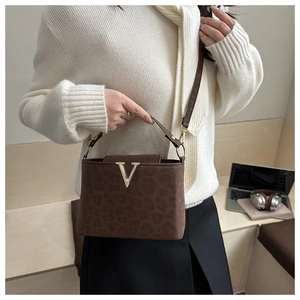 Détail d'un sac à main léopard marron avec fermoir en V doré et fine bandoulière élégante