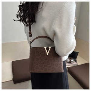 Détail du sac bandoulière léopard avec boucle en V dorée porté par un mannequin