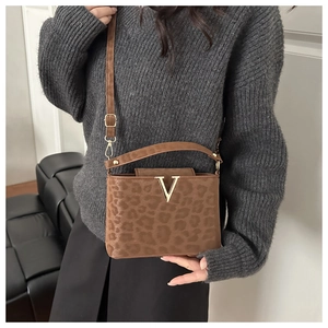 Détail d'un sac léopard avec boucle en V dorée et texture en peluche douce