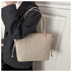 Detail of a large cream tote bag with adjustable drawstring accents and matte texture