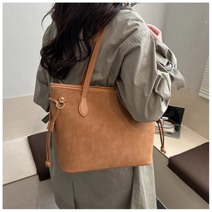Brown suede tote bag shown on shoulder in a professional office setting with a laptop