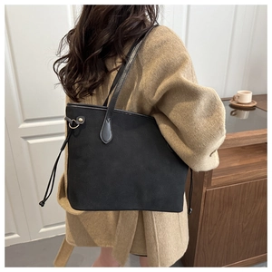 Detail of black matte tote bag with drawstring and gold hardware worn by female model