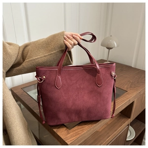 Close-up of burgundy tote bag with mixed suede leather texture and gold buckle detail