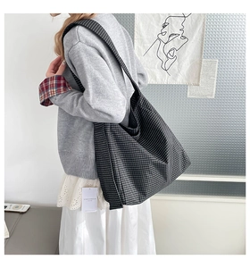 Detail of minimalist black and white checkered tote bag showing strap and fabric texture