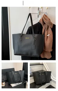 Detail view of a black tote bag with long straps and gold foil lettering on leather texture