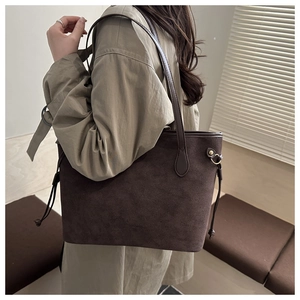 Close-up of deep brown suede tote bag featuring side drawstrings and gold hardware