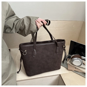 Close-up of large dark brown tote bag with matte texture and gold hardware details