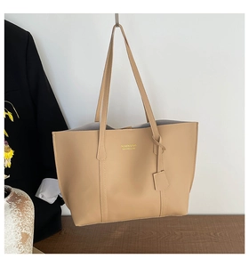 Gros plan du cabas en cuir beige avec lettrage doré et pendentif décoratif détaillé