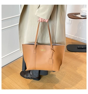 Détail d'un grand sac cabas marron avec logo doré et fines bandoulières élégantes