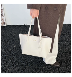 Detailed view of cream leather tote bag featuring Fashion & Bag text held by a model