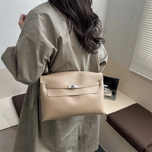 Sac bandoulière beige chic avec fermoir métallique porté par un mannequin en intérieur