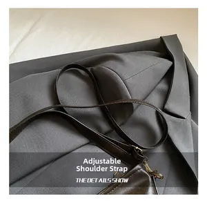 Détail de la bandoulière réglable en cuir avec boucle dorée vintage sur un sac marron