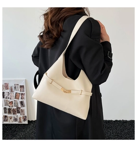 Dettaglio elegante borsa tote in pelle crema con fibbia dorata sulla spalla del modello