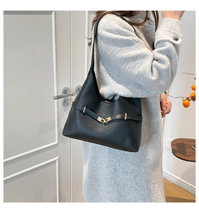 Dettaglio borsa a spalla in pelle nera con fibbia dorata su un cappotto di lana grigio