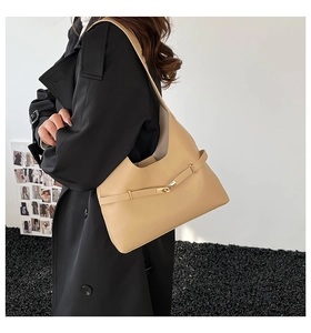 Dettaglio della borsa hobo beige con fibbia in metallo dorato su trench nero elegante