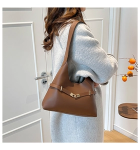 Borsa a spalla marrone in finta pelle con fibbia dorata e cinturino su un cappotto invernale