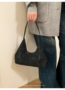 Detail of minimalist retro black jacquard monogram tote bag with leather shoulder strap